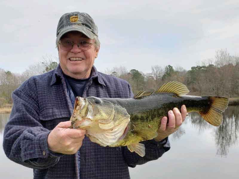 largemouth bass angler holds up his catch