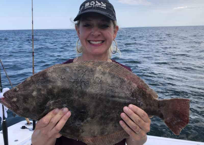 angler holds up a flounder