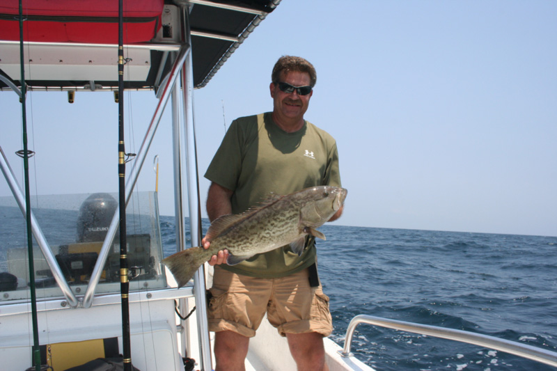 grouper angler holds up fish