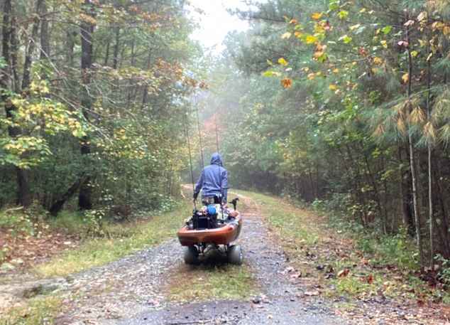 wheeling a kayak through the woods to go fishing