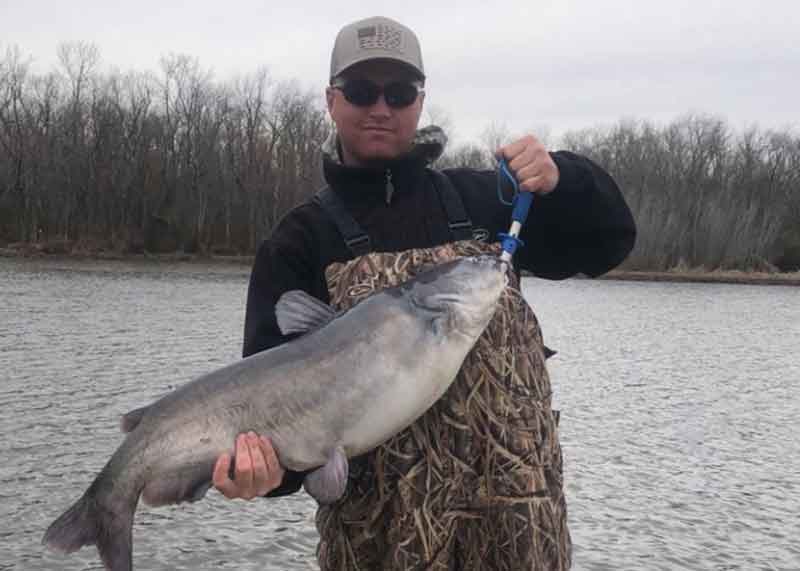 angler holds up a fat catfish