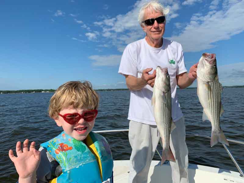 grandfather and grandson with striped bass they caught