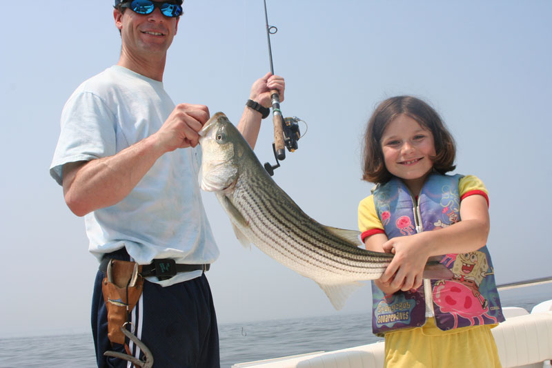 kid with a striped bass caught while fishing on chesapeake bay