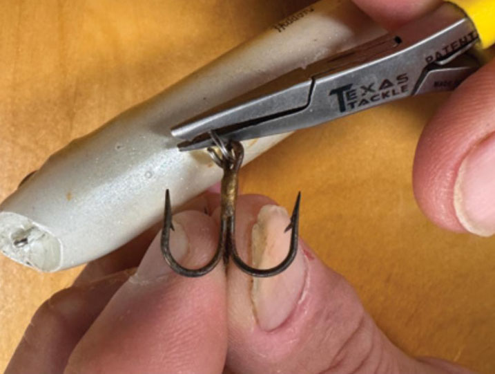 opening the split ring to remove treble hook from fishing lure