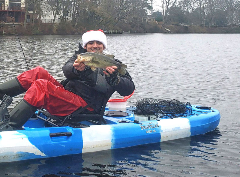angler with a largemouth bass he caught in winter